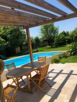 una mesa de madera y sillas bajo una pérgola de madera en Villa d&#39;architecte avec piscine et grand jardin, en Marsella