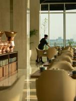 un hombre sentado en una silla en una habitación con mesas en Trembesi Hotel, en Serpong