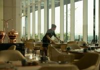 un hombre parado frente a las mesas en un restaurante en Trembesi Hotel, en Serpong