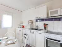 a white kitchen with white appliances and a table at Apartment Eden Roc 2 by Interhome in Narbonne-Plage