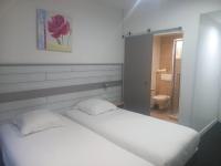 a white bedroom with two beds and a bathroom at Hôtel Akena Le Touquet-Camiers in Camiers