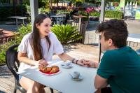 un hombre y una mujer sentados en una mesa con un plato de comida en hu Roma Camping In Town, en Roma