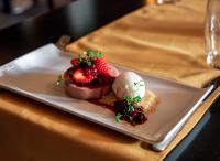 a plate with strawberries and ice cream on a table at Trenython Manor Resort in Fowey
