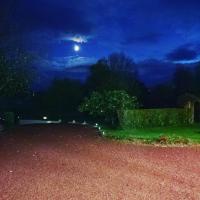a night time view of a garden with the moon at La Minoterie in Tessy-sur-Vire