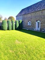 a yard with a brick building and a row of bushes at La Minoterie in Tessy-sur-Vire