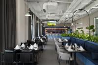 a restaurant with black tables and white chairs and plants at DDK Hotel Duhok in Duhok