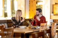 トゥルラッハー・ヘーエにあるHotel Turracherhofのワイングラスを持ってテーブルに座っている男女