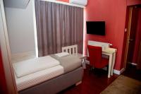 a bedroom with a bed and a desk with a red wall at So&sol boutique Hotel, Tuzla in Tuzla