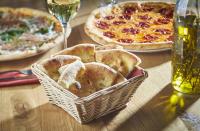 Una mesa con dos pizzas y una cesta de pan. en AlpenParks Hotel & Apartment Central Zell am See, en Zell am See