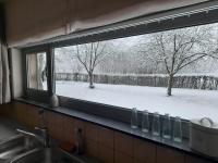 a kitchen window with a view of a snow covered yard at Vakantiewoning De Luysmolen in Bocholt