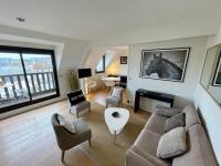 a living room with a couch and a horse picture on the wall at Deauville Harmonie - Tout à pied, Balcon &amp; Modernité in Deauville