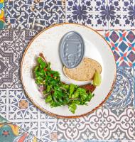 a plate of food with a spoon and greens on a table at Hotel Natalia 18 in Lviv