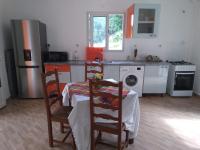 eine Küche mit einem Tisch, 2 Stühlen und einem Herd in der Unterkunft Le papillon bleu in Sainte-Anne