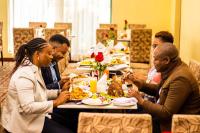 a group of people sitting at a long table eating food at Gold Crest Hotel - Arusha in Arusha