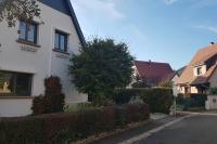 a white house with a hedge next to a street at Studio Marie-Rose in Ribeauvillé