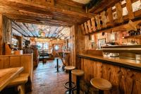 un restaurante con paredes de madera y un bar con taburetes en Hotel Restaurant Hexenalm, en Söll