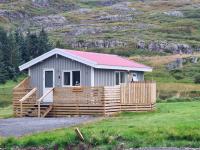 a small house with a fence in a field at Hvammur 3 Hrakhólar with private hot tub in Kaldrananes