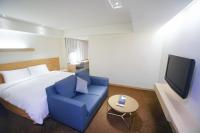 a bedroom with a bed and a blue chair and a tv at Beacon Hotel in Taichung
