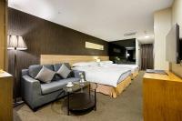 a hotel room with a bed and a couch at Beacon Hotel in Taichung