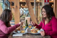 纳塔列斯港Hostal Boutique Factoria Patagonia的两个坐在桌子边的女人,拿着食物和饮料