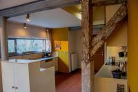 a kitchen with yellow walls and a wooden beam at Vakantiewoning De Luysmolen in Bocholt