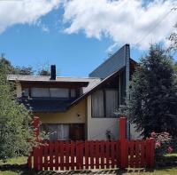 a house with a red fence in front of it at Cabañas Gnionguis in Villa La Angostura