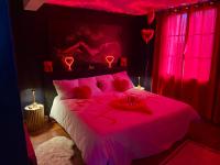 a bedroom with a pink bed with red lighting at Escapade jacuzzi in Caen
