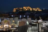 a restaurant with tables and chairs with a view of the acropolis at Titania Hotel in Athens