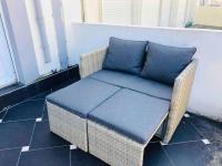 a wicker chair with a blue cushion on a porch at Appartement A confortable et lumineux in Neufchâtel-Hardelot