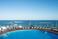Una piscina con sillas y el océano al fondo. en Hotel El Puerto by Pierre Vacances, en Fuengirola