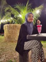 a woman sitting at a table with a drink at Dangau Sala D'Kontena in Alor Setar