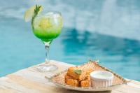 - une boisson et une assiette de nourriture sur une table à côté de la piscine dans l'établissement Makkai Resort Hotel Bombinhas, à Bombinhas