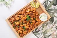 un plateau de calamars frits avec des quartiers de citron vert et une sauce dans l'établissement Makkai Resort Hotel Bombinhas, à Bombinhas