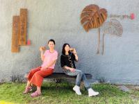 two women sitting on a bench in front of a wall at 輕塵別院Serenegray B&amp;B in Wujie