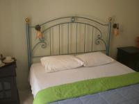 a bed with a metal headboard and white pillows at Loukas Inn Family Resort in Keri