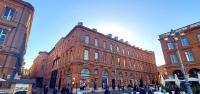 トゥールーズにあるPlaza Hotel Capitole Toulouseの街の通りにある大きな赤レンガの建物