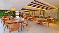 una sala da pranzo con tavoli e sedie in legno di MANA BEACH EXPERIENCE by AFT Porto de Galinhas, Muro Alto a Porto De Galinhas