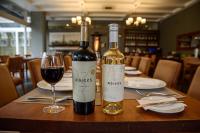 two bottles of wine sitting on a table with a glass at Hotel Boutique Raíces in Curicó