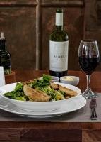 a plate of food on a table with a bottle of wine at Hotel Boutique Raíces in Curicó