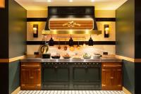 uma cozinha com armários de madeira e um fogão em Ours Blanc Hotel & Spa em Les Menuires