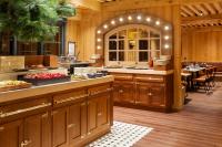 uma cozinha com armários de madeira e uma mesa com comida em Ours Blanc Hotel & Spa em Les Menuires