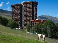 a horse standing in a field in front of a building at Studio Pegase Phenix-44 by Interhome in Le Corbier