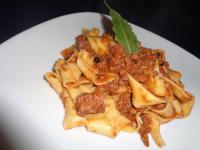 Un plato de pasta con salsa de carne y una hoja verde. en Hotel Rosati, en Chiusi
