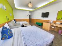 a bedroom with a bed and a desk and a television at Xing Ji Hotel in Kenting