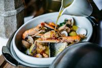 a bowl of seafood with a sauce being poured onto it at Apartment Petra IV in Dubrovnik