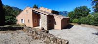 a small house with a stone wall in a yard at La Peyreyre in Jaujac