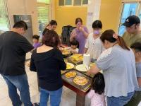 a group of people standing around a table with pizzas at 光腳丫宜蘭民宿 in Dongshan