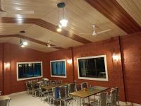 una sala da pranzo con tavoli e sedie in legno di Sk Resort ad Alibaug