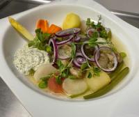 Un tazón blanco de comida con verduras en un plato. en L'auberge fleurie, en Heilly