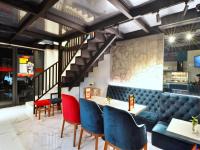 Un restaurante con sillas y mesas y una escalera. en MORITZ INN BSD TANGERANG, en Tangerang
